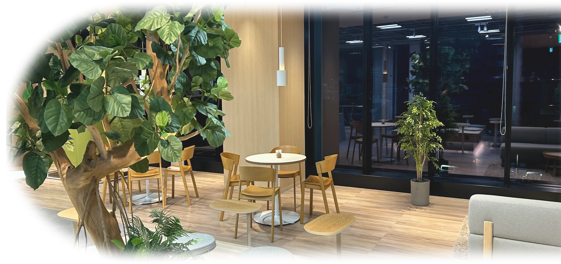 観葉植物と木の家具で設えた明るいオフィスのラウンジ