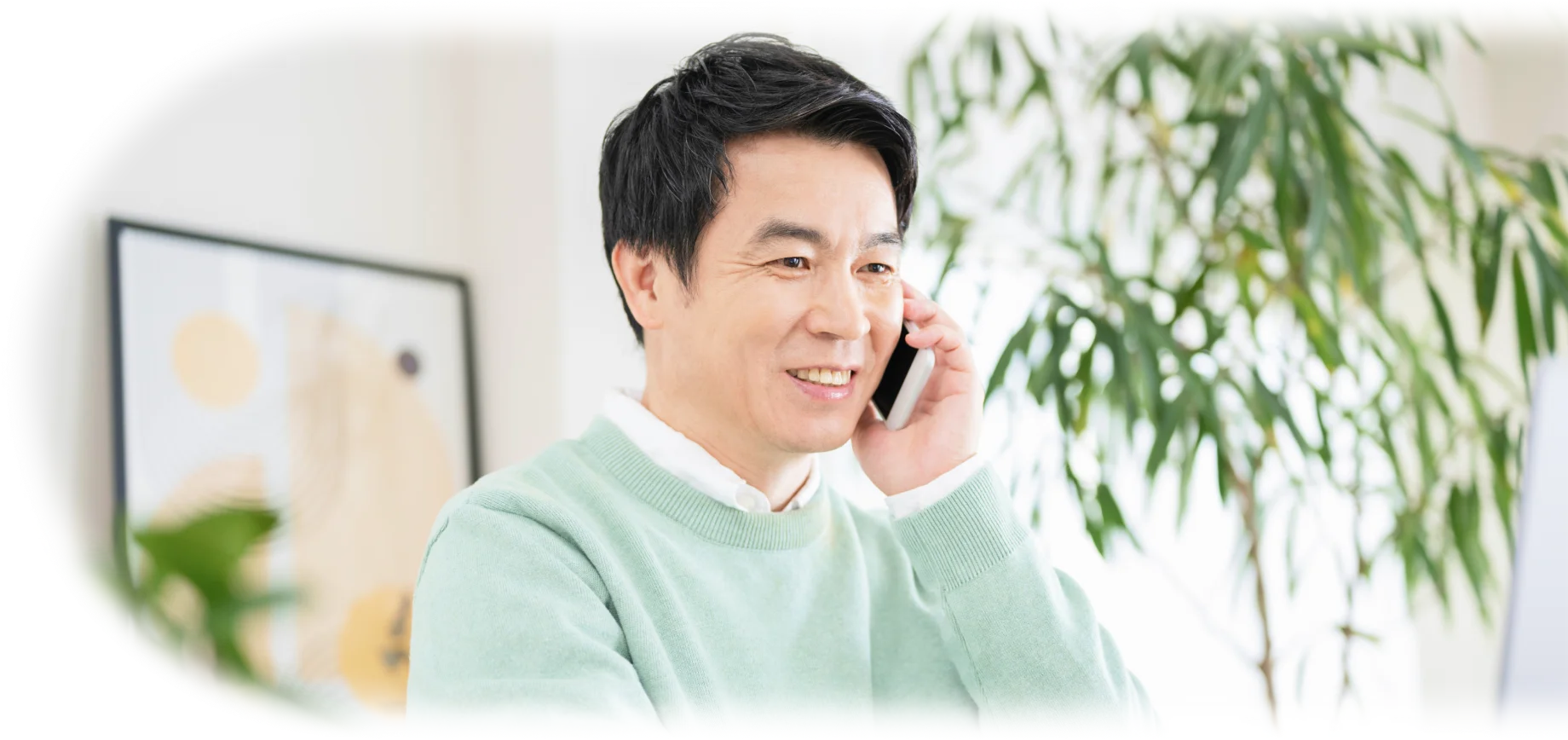 スマートフォンを耳に当てて笑顔で会話する男性